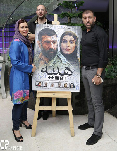 علی انصاریان و ماهچهره خلیلی در کنار پوستر امضا شده فیلمشان