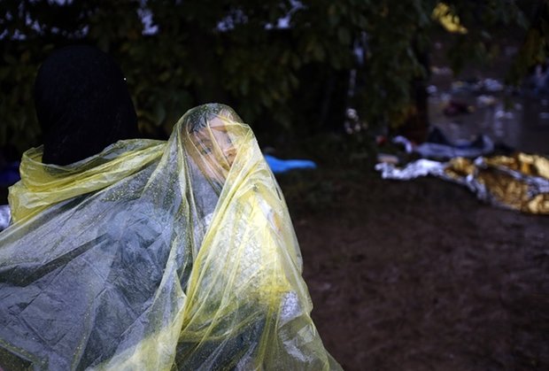 مهاجران با پلاستیک خود را در مقابل باران حفظ می‌کنند