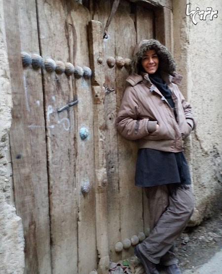 بیتا بادران در کنار یک درب چوبی قدیمی در پشت صحنه کار جدیدش