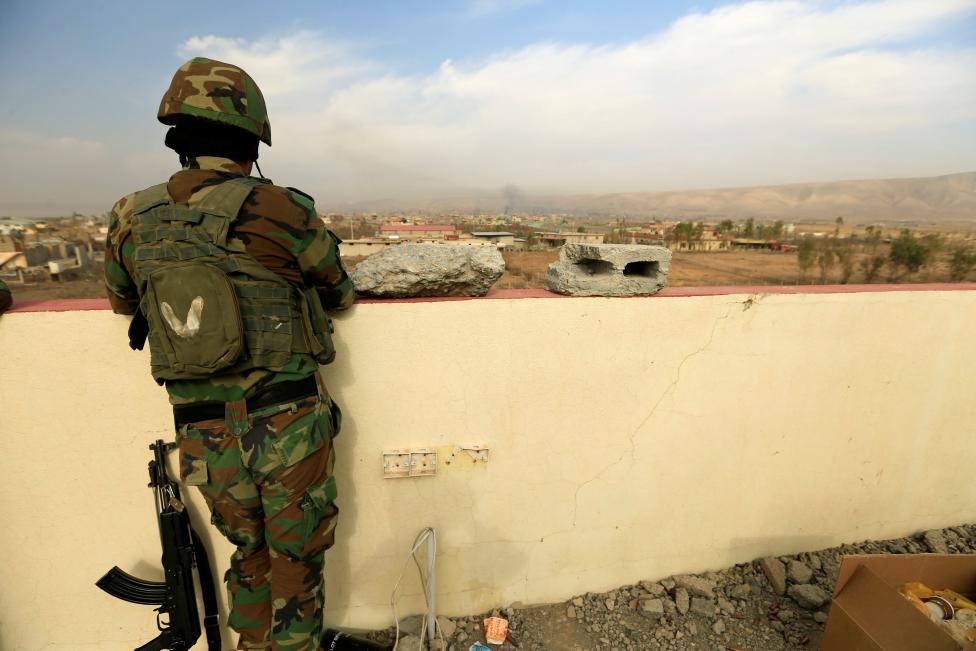 A member of Peshmerga forces stands on a building in the town of Bashiqa, east of Mosul