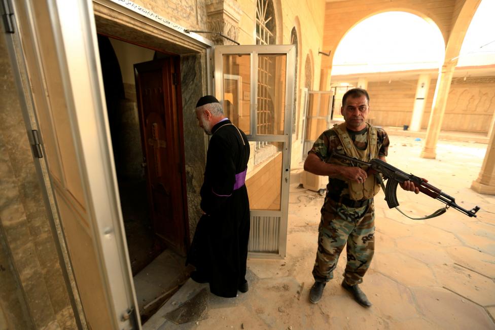 Priests with Peshmerga forces inspect the Mart Shmoni Church since it was recaptured from the Islamic State in the town of Bashiqa