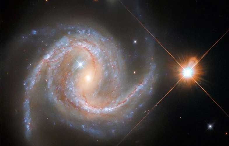 درخشش یک ستاره در کنار کهکشانی مارپیچی